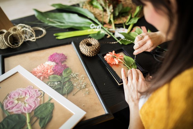 女性が押し花を作成している様子。色とりどりの花がフレームに配置されている。